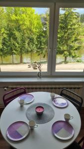 einem Tisch mit Platten vor einem Fenster in der Unterkunft Dwupokojowy Apartament z widokiem na kanał Augustowski in Augustów