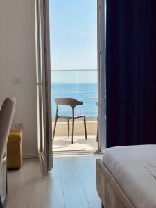 a bedroom with a view of the ocean and a chair at Ionian Terrace in Himare