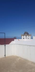 eine weiße Wand mit einem Gebäude im Hintergrund in der Unterkunft Appartement 2 éme étage dans la médina kédima in Asilah