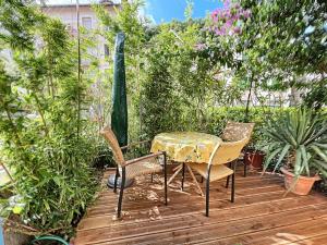 uma mesa e cadeiras num deque de madeira com plantas em Appart très cosy et confortable à Amélie les Bains em Amélie-les-Bains-Palalda