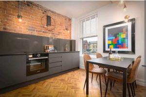 a kitchen with a dining table and a brick wall at Capri Stays - Apartment Two - Two Bed Apartment in Blackpool