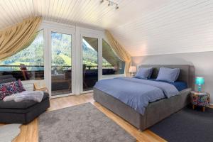 a bedroom with a bed and a couch and windows at Rož'ca apartments with mountain view in Mojstrana