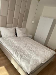 a bedroom with a large bed with white sheets at Apartament Lili Słoneczne Tarasy in Dziwnówek
