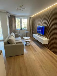 a living room with a couch and a tv on a wall at Apartament Lili Słoneczne Tarasy in Dziwnówek