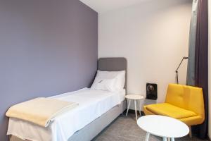 a small bedroom with a bed and a yellow chair at Boutique hotel Lili in Rovinj