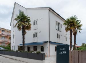 a white building with palm trees in front of it at Boutique hotel Lili in Rovinj