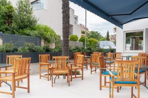 a group of wooden chairs and tables and a blue umbrella at Boutique hotel Lili in Rovinj