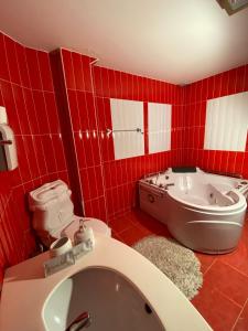 a red tiled bathroom with a toilet and a tub at Hotel Sara & SPA in Pristina