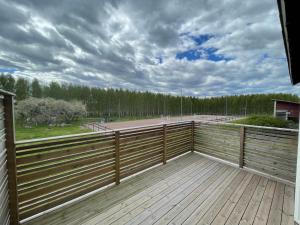um grande deque com uma cerca de madeira e árvores em Hälla 1 nära jönåkers golfbana em Jönåker