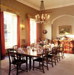 uma sala de jantar com uma mesa e cadeiras e um lustre em Lismacue House em Bansha