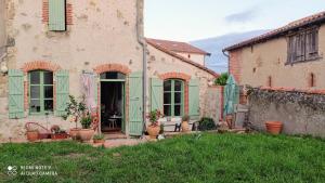an old house with green shutters and plants in a yard at St ybars chez Annick et Alain in Saint-Ybars