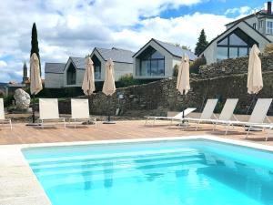 a pool with chairs and umbrellas next to a house at Miradores do Sil Hotel Apartamento in Cristosende