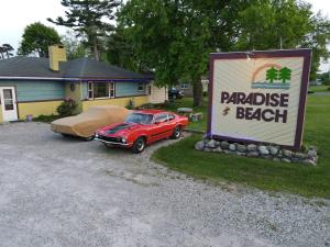 un coche aparcado frente a una casa con un cartel en Paradise Beach resort, en Tawas City