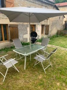 einen Tisch und Stühle mit einem Sonnenschirm und einem Grill in der Unterkunft Petite maison lorraine avec cheminée et jardin in Saint-Mihiel