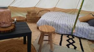 1 dormitorio con cama, mesa y taburete en Glamping Zonnebloem - Back-to-Nature, en Herzele