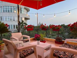 un patio con mesa, sillas y sombrilla roja en Don Robert Apartment en Durrës