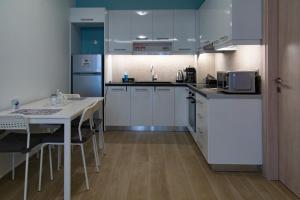 a kitchen with white cabinets and a table with a microwave at Chelidoni apartment ground floor in Heraklio Town