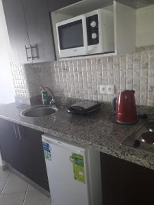 - un comptoir de cuisine avec évier et four micro-ondes dans l'établissement Charmant Studio piscine mdiq CaboNégro Martil, à Cabo Negro