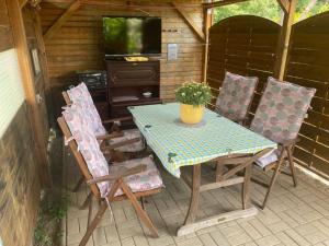 eine Terrasse mit einem Tisch und Stühlen sowie einem TV in der Unterkunft Ferienhaus am Mühlgraben in Thale