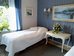 a bedroom with a white bed and a table at Kulttuurikartano Pekan Pirtit in Haapavesi