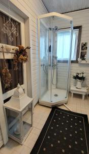 a bathroom with a shower with a table and a rug at Kulttuurikartano Pekan Pirtit in Haapavesi