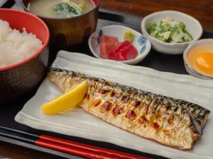 a plate of fish with a lemon and other bowls of food at APA Hotel Tokyo Kudanshita in Tokyo