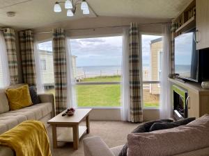 a living room with a view of the ocean at New Sea View Platinum Caravan with Huge Decking in Newcastle upon Tyne