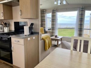 a kitchen and living room with a view of the ocean at New Sea View Platinum Caravan with Huge Decking in Newcastle upon Tyne
