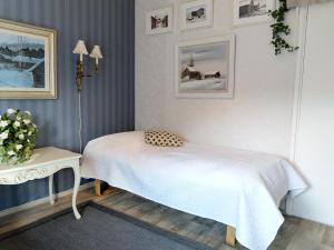 a bedroom with a white bed and a table at Kulttuurikartano Pekan Pirtit in Haapavesi
