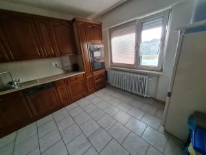 a kitchen with wooden cabinets and a tile floor at Ferienwohnung Ramstein in Ramstein-Miesenbach