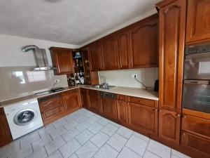 eine Küche mit Holzschränken, einer Waschmaschine und einem Trockner in der Unterkunft Ferienwohnung Ramstein in Ramstein-Miesenbach