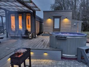 a tiny house with a hot tub on a deck at Purenes - Barrel shaped pod with hot tube in Sliseri