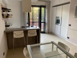 a kitchen with white cabinets and a glass table in it at Appartamento L'Olivo in Latina