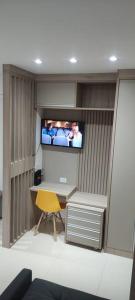 Zimmer mit einem Schreibtisch und einem TV an der Wand in der Unterkunft La Home House6 - Apto Studio Completinho com elevador em SJP - 10 minutos Aeroporto Afonso Pena - Curitiba in São José dos Pinhais