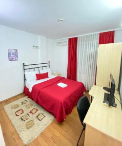 a bedroom with a bed with a red blanket and a desk at Hotel Sara & SPA in Pristina