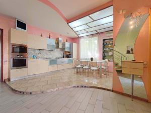 a large kitchen with pink walls and tables and chairs at Приватний котедж з Басейном біля моря Совіньон Одеса in Odesa