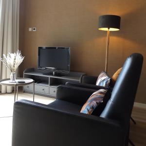 a living room with a black couch and a tv at Het Broekeroord in Wezep