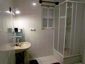 y baño blanco con lavabo y ducha. en Leander Vendeghaz en Gyenesdiás