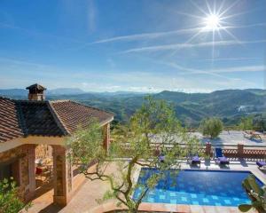 a villa with a swimming pool and mountains in the background at La Olgava in El Gastor