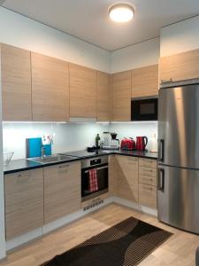 a kitchen with wooden cabinets and a stainless steel refrigerator at Modern city apartment with Sauna nearby the Airport in Vantaa