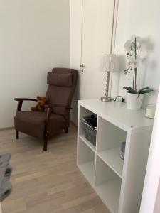a living room with a chair and a white table at Modern city apartment with Sauna nearby the Airport in Vantaa