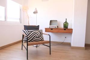 a chair in a room with a desk and a laptop at A Nossa Casa da Costa in Costa da Caparica +13 photos