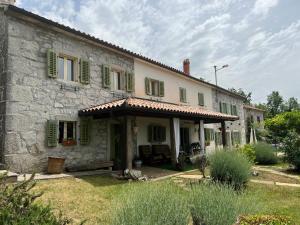 una vieja casa de piedra con persianas verdes. en Holiday Home Villa Mavrici, en Buzet