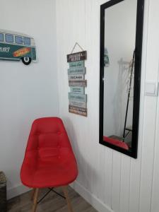 une chaise rouge dans une pièce avec un miroir dans l'établissement The Violet House, à Costa Nova