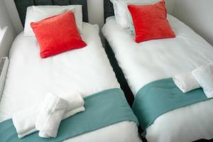 Duas camas individuais com almofadas vermelhas e brancas. em 3 BED new build home with FREE parking BHX NEC HS2 CONTRACTORS FAMILIES em Solihull