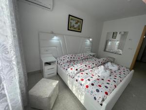 - une chambre blanche avec un lit doté de points de polka rouge dans l'établissement ROMANCE Apartments, à Tirana