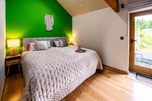 a bedroom with a large bed with a green wall at Romantic Snowdonia Cottage with Hot tub, sea & mountain views in Tywyn