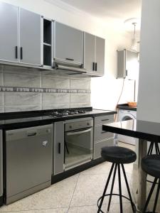 una cucina con armadi bianchi e un tavolo con sgabelli di T3 beautiful apartment for rent a Martil