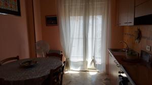 チェファルにあるCASA FLORIDEA -Mediterranea Sicilia Aptのキッチン(テーブル付)、窓(カーテン付)