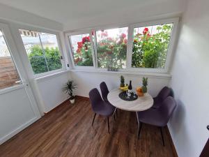 a dining room with a table and chairs and windows at Apartmani Lovre i Zara in Zadar